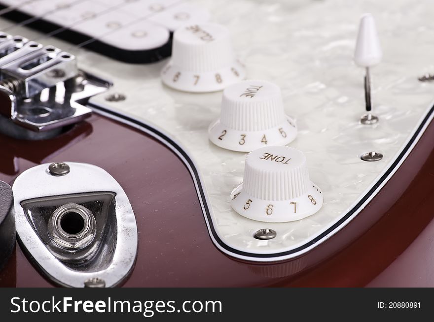 Detail of electric red and white guitar with volume and tone knobs. Detail of electric red and white guitar with volume and tone knobs