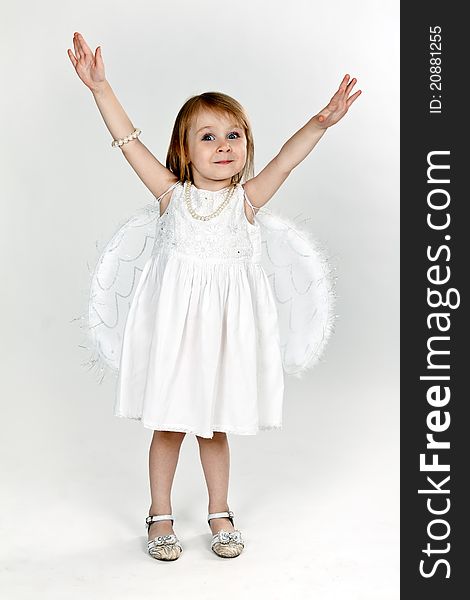 Little girl with angel wings in the studio on a gray background