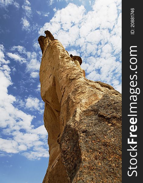 Close up and unusual angle of foot to top of fairy chimney into the clouds of Cappadocia, Turkey, portrait, crop space, copy space with blue cloudy sky. Close up and unusual angle of foot to top of fairy chimney into the clouds of Cappadocia, Turkey, portrait, crop space, copy space with blue cloudy sky