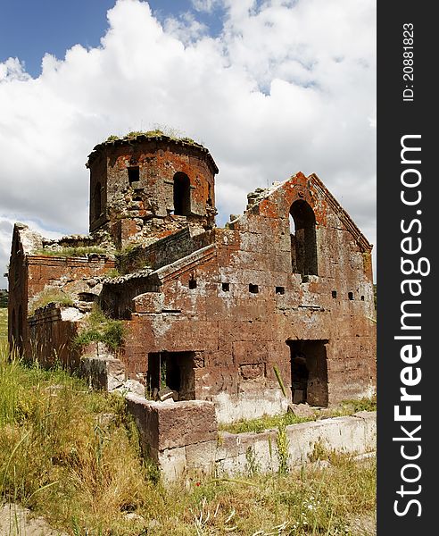 Portrait of Kizil Kilsie with tall grass, Red Church ruins of dilapidated and derelict Church Cappadocia Turkey dating to the 6th century, rustic colors, red limestone, tall grass, crop area and copy space. Portrait of Kizil Kilsie with tall grass, Red Church ruins of dilapidated and derelict Church Cappadocia Turkey dating to the 6th century, rustic colors, red limestone, tall grass, crop area and copy space