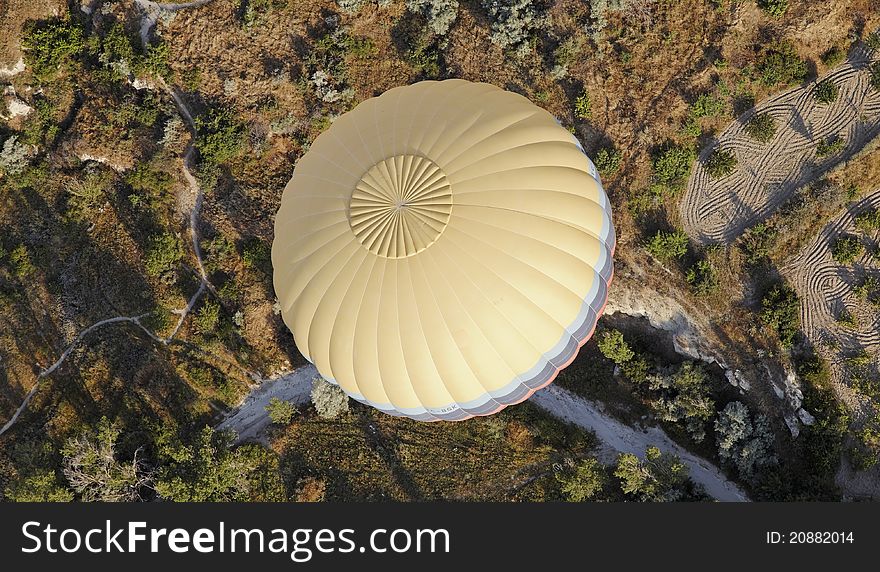 Multi Color banded yellow hot air balloon over the wilderness of Cappadpcia, showing wilderness and farmlands, landscape, crop space, copy space. Multi Color banded yellow hot air balloon over the wilderness of Cappadpcia, showing wilderness and farmlands, landscape, crop space, copy space