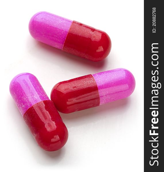 Bunch of red and pink capsules on white background.