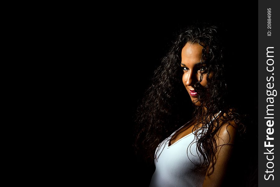 Brazilian girl with tight dark curls looks into camera. Wearing a white vest and a cheeky smile. Brazilian girl with tight dark curls looks into camera. Wearing a white vest and a cheeky smile.