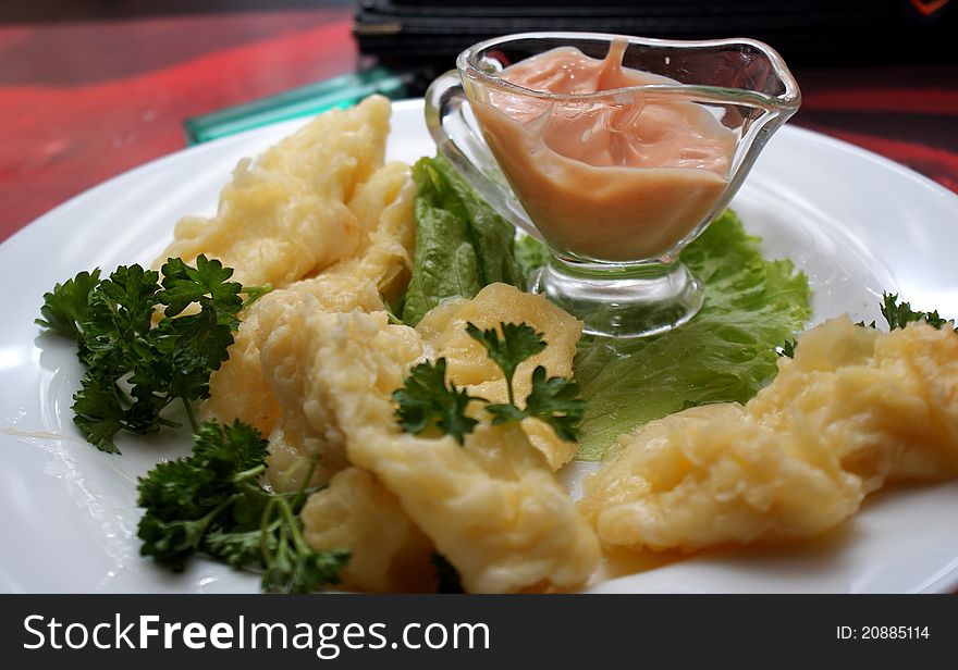 Pieces of cheese on the plate with lettuce and sauce. Pieces of cheese on the plate with lettuce and sauce