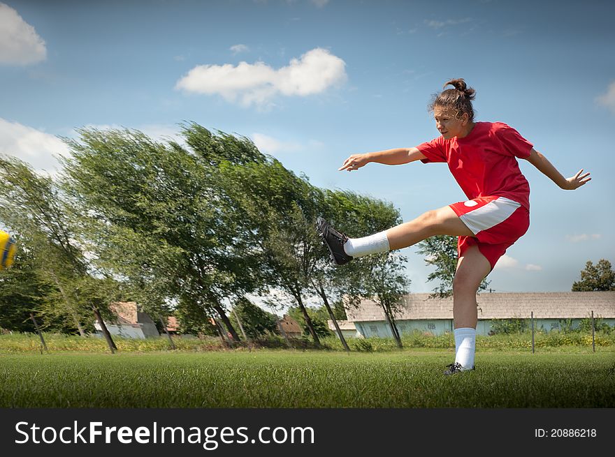 Young girl kicking soccer ball on field