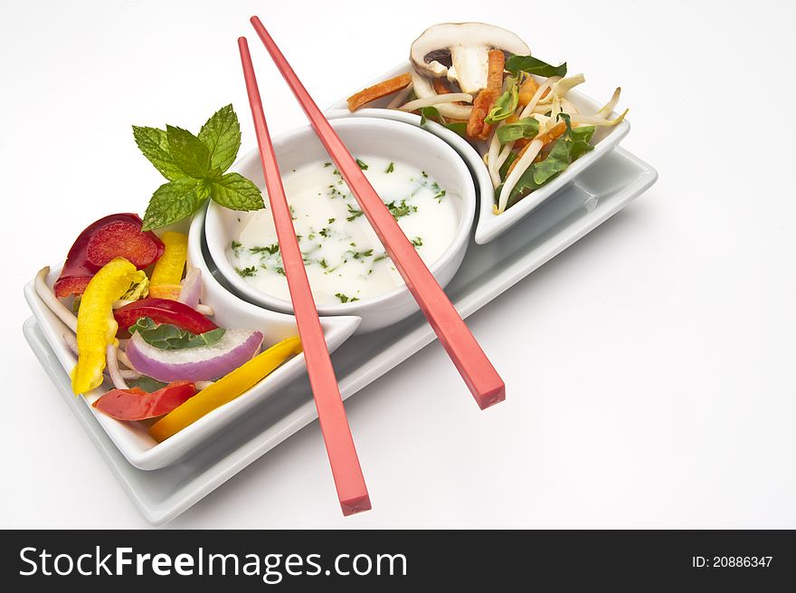 Mixed salad with a dip in white bowls with chopsticks on a white background. Mixed salad with a dip in white bowls with chopsticks on a white background