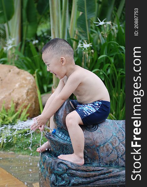 Little boy plays with water jet from fish-shape hose outdoors. Little boy plays with water jet from fish-shape hose outdoors