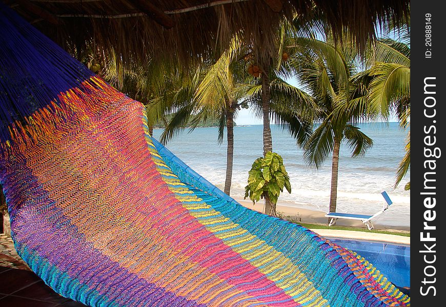 Rainbow colored hammock on pacific ocean with pool palm trees and beach chair. Rainbow colored hammock on pacific ocean with pool palm trees and beach chair