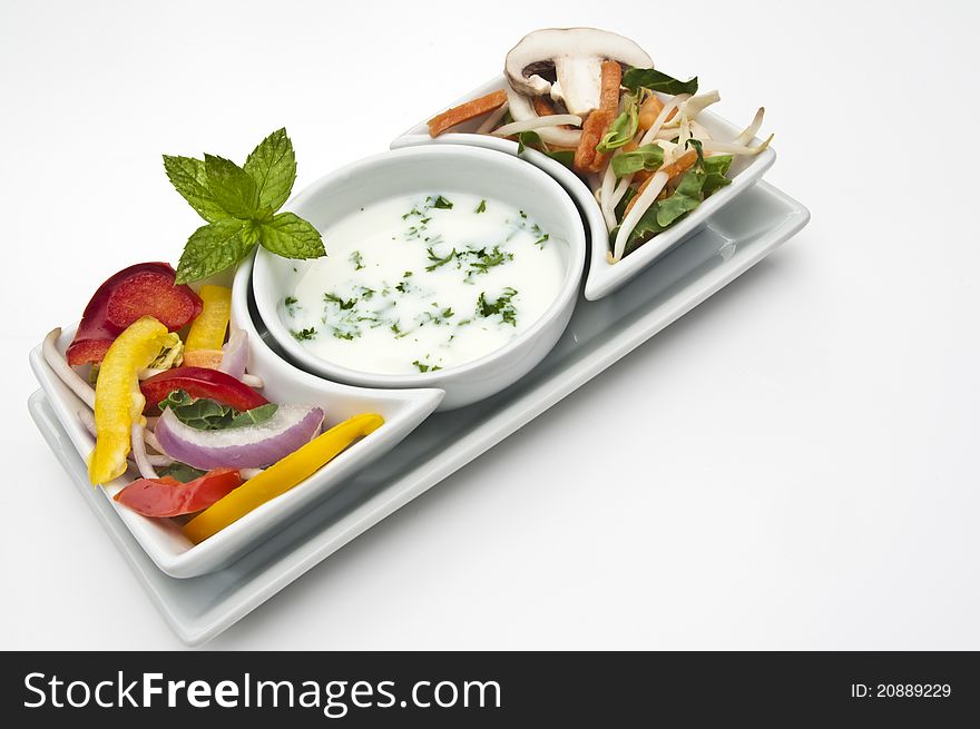 Fresh mixed salad and dip in white bowls on a white background