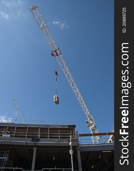 A White Tower Crane lifting an air conditioning unit on a consruction site. A White Tower Crane lifting an air conditioning unit on a consruction site