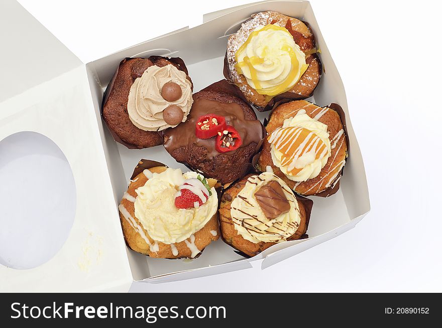 Cupcakes of different flavours in a freshly opened box slightly squashed. Cupcakes of different flavours in a freshly opened box slightly squashed