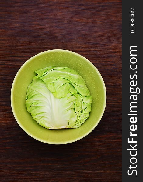 Image of white cabbage in a deep plate over wooden background