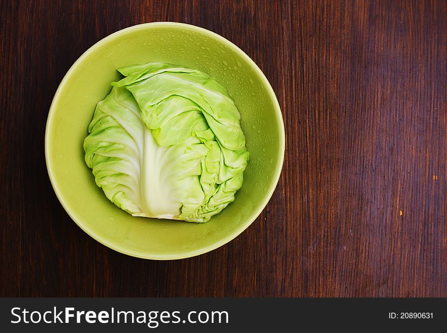 Image of white cabbage in a deep plate over wooden background