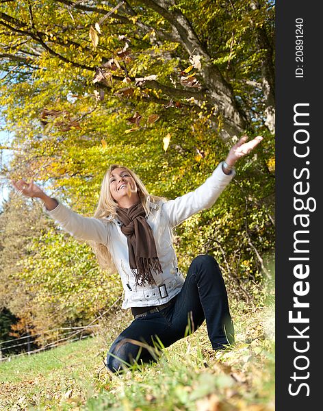Young blond woman throwing leaves into the air. Young blond woman throwing leaves into the air