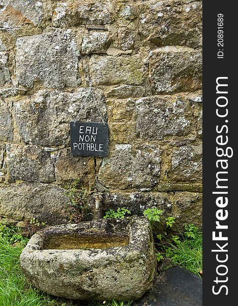 A French sign above an old basin and tap. A French sign above an old basin and tap