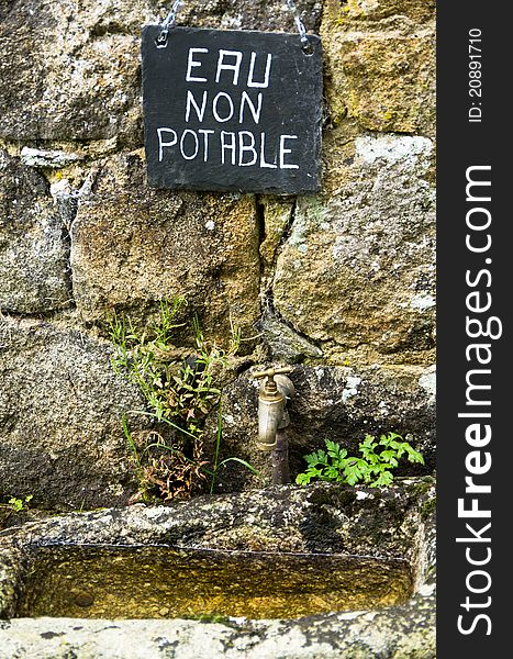 A French sign above an old basin and tap. A French sign above an old basin and tap