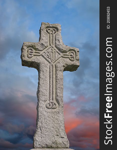 Irish granite celtic cross with traditional carved designs against a colourful stormy sky. Irish granite celtic cross with traditional carved designs against a colourful stormy sky