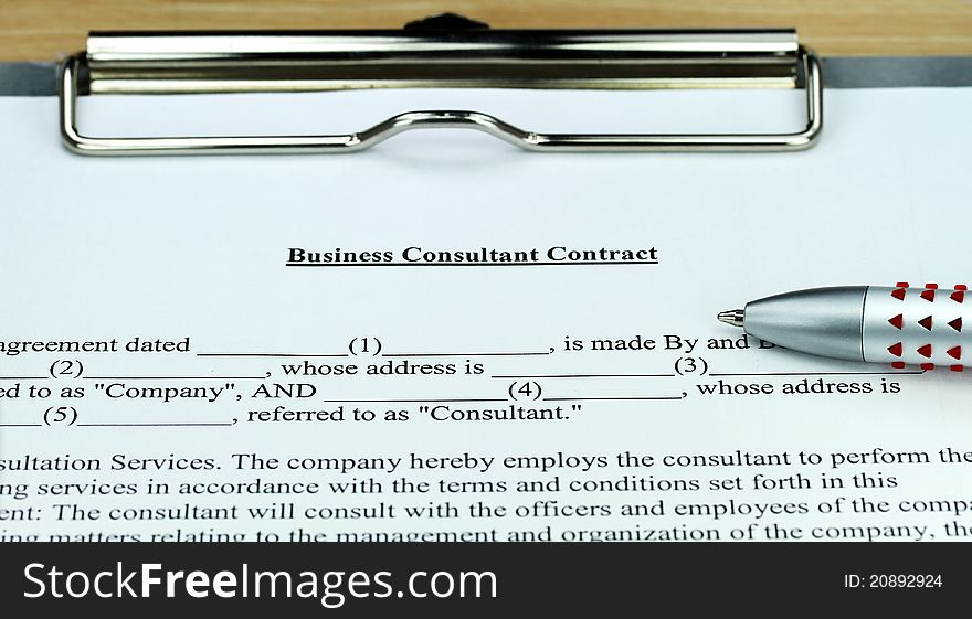 A Business Consultant form ready for you to sign, showing the form, ball point pen on a metal clipboard. A Business Consultant form ready for you to sign, showing the form, ball point pen on a metal clipboard.