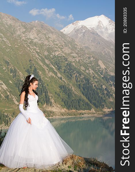 Woman in a wedding dress in the valley of the mountains. Woman in a wedding dress in the valley of the mountains