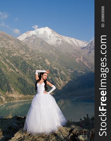 Beautiful bride in a long white dress against the backdrop of the lake and mountains. Beautiful bride in a long white dress against the backdrop of the lake and mountains