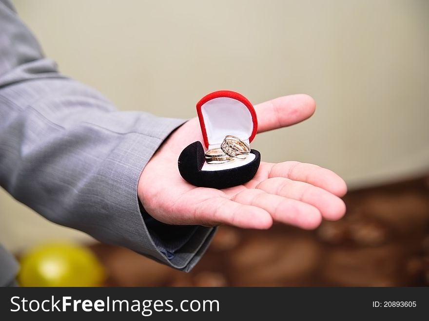 Hand of groom holding a box with a wedding bands