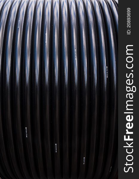 Black electric cable rolled in reel pattern vertical. Black electric cable rolled in reel pattern vertical