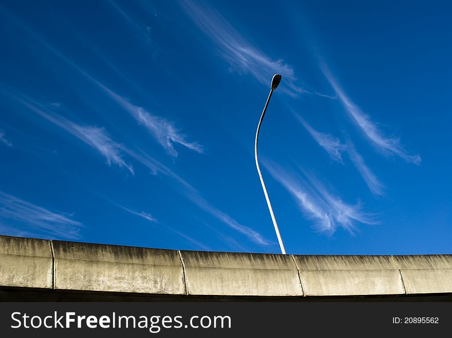 Crazy clouds on a blue sky over a bridge with a light post