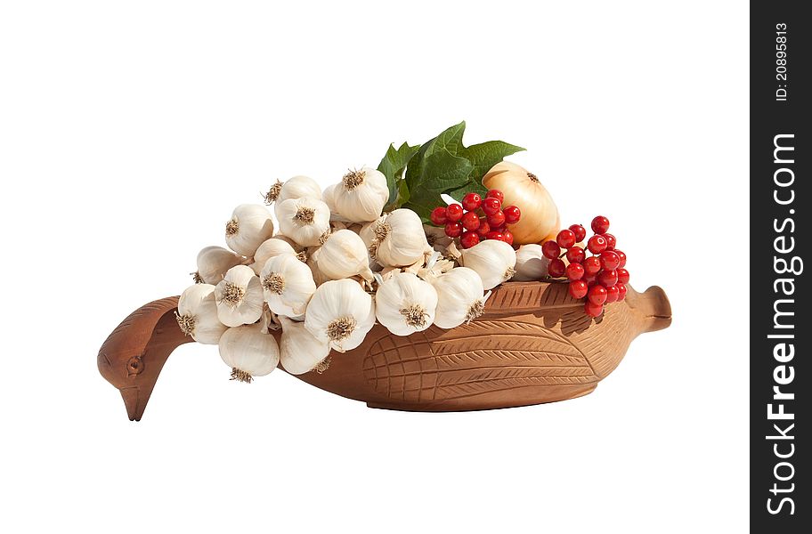 The still life from the garlic, onions, decorated with viburnum in the wooden dishes