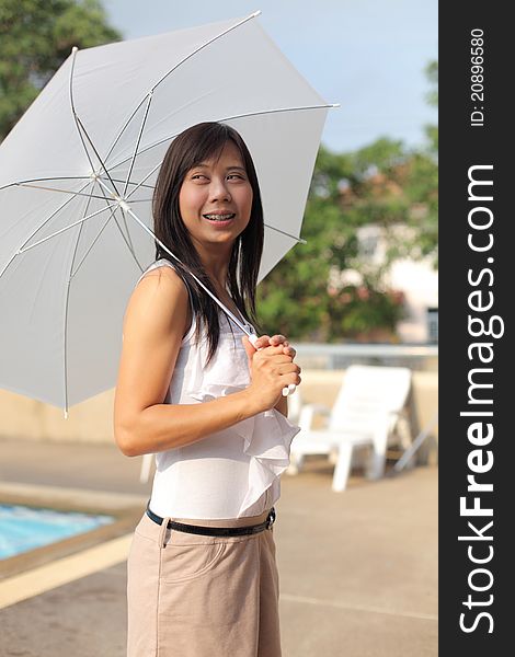 Women and umbrella beside swimming pool with smilling