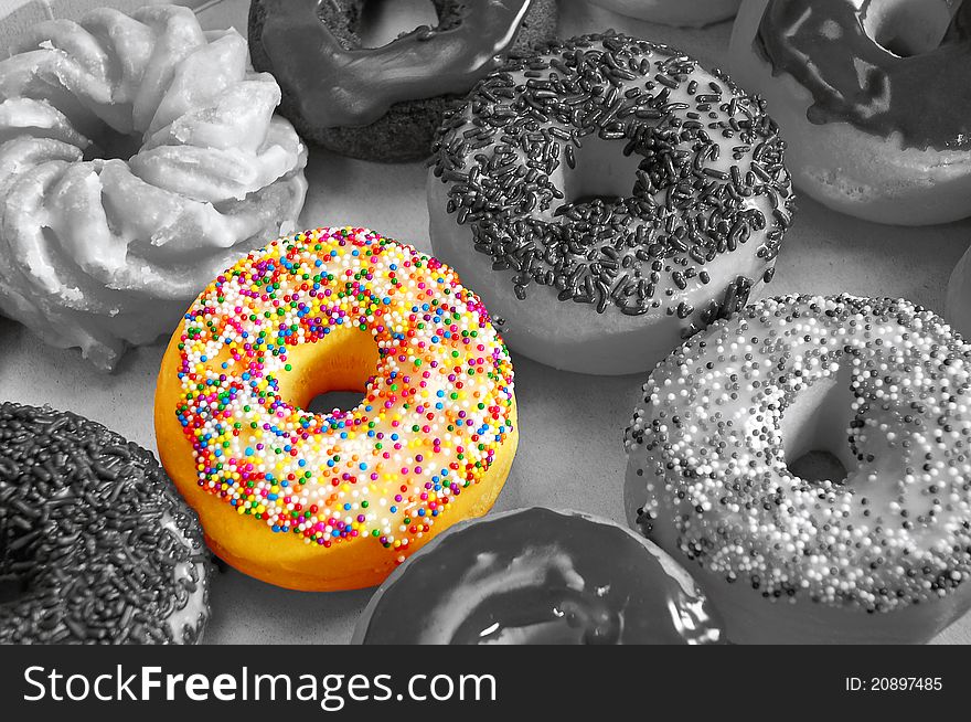 Assortment of donuts in black and white with one donut in color. Assortment of donuts in black and white with one donut in color