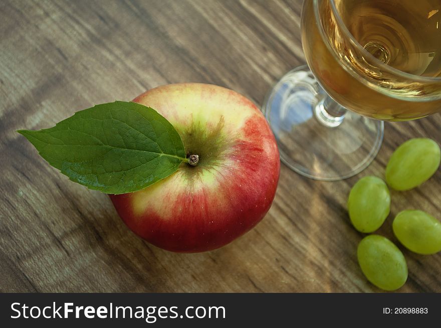 Red apple and grapes on a wooden background. Red apple and grapes on a wooden background