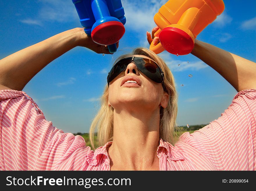 Beautiful woman watering herself at hot summer day