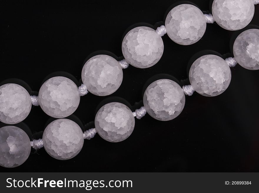 Round beads of cracked translucent white agate on black background. Round beads of cracked translucent white agate on black background