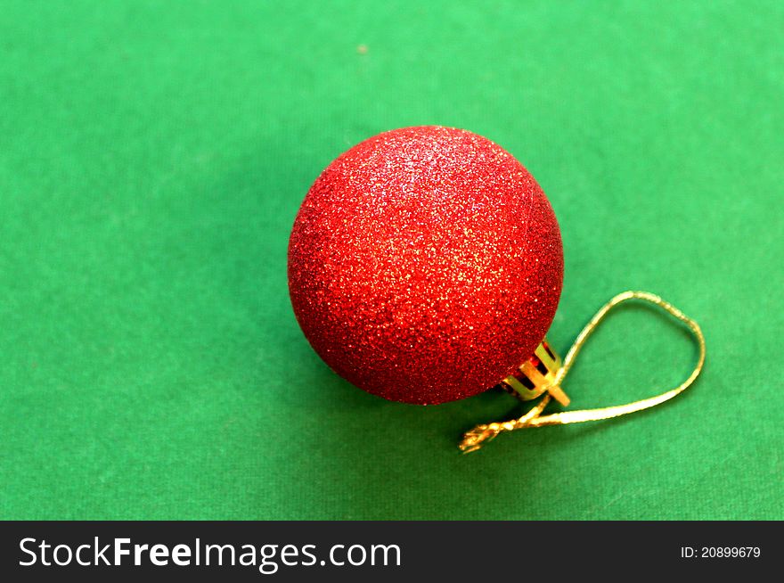A glittering red christmas ball on green background. A glittering red christmas ball on green background