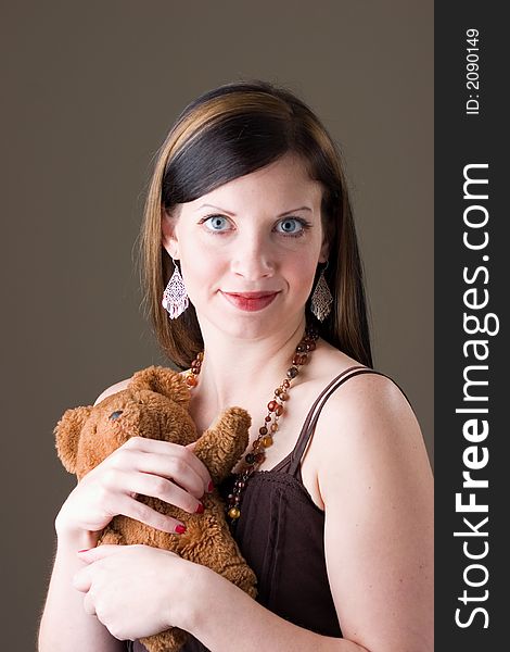 An attractive young brunette woman holding a favorite brown teddy bear. An attractive young brunette woman holding a favorite brown teddy bear