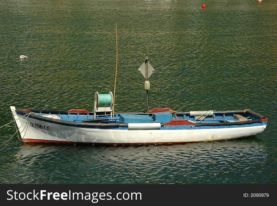 Wood boat floating on the water outside of a an Azores dock. Wood boat floating on the water outside of a an Azores dock