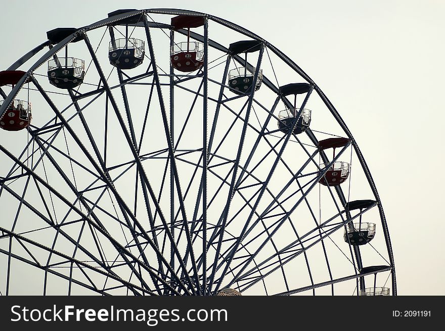 Ferris wheel silhouette against a bright sky