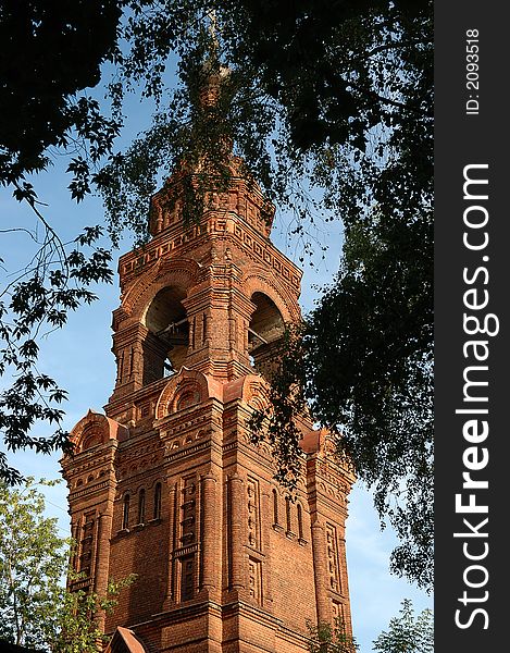 Orthodox brick church between tree leaves. Orthodox brick church between tree leaves