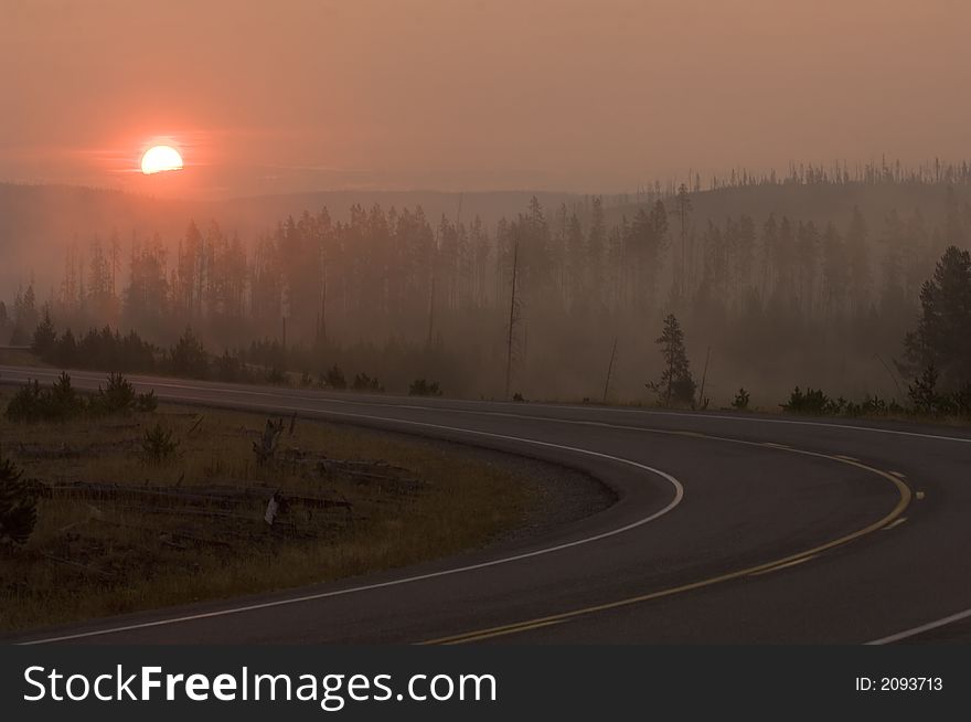 The sun rises over a roadway in Yellowstone national park. The sun rises over a roadway in Yellowstone national park