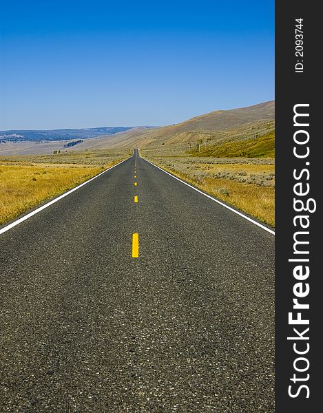 The road leading through the open space of Lamar Valley in Yellowstone National Park. The road leading through the open space of Lamar Valley in Yellowstone National Park