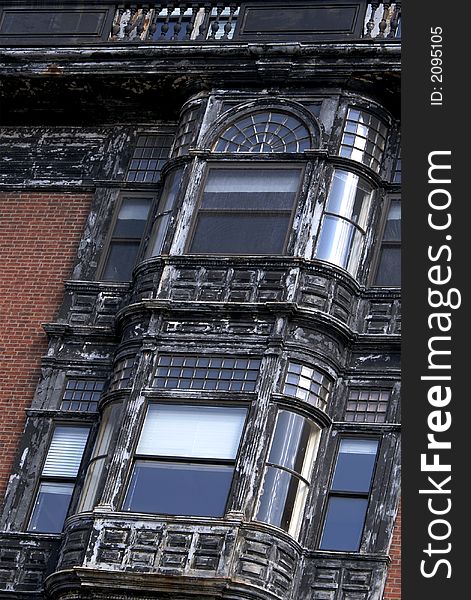 Detail of old bowed windows on brownstone building in boston, smaller windows have many panes, shade is puled half way down