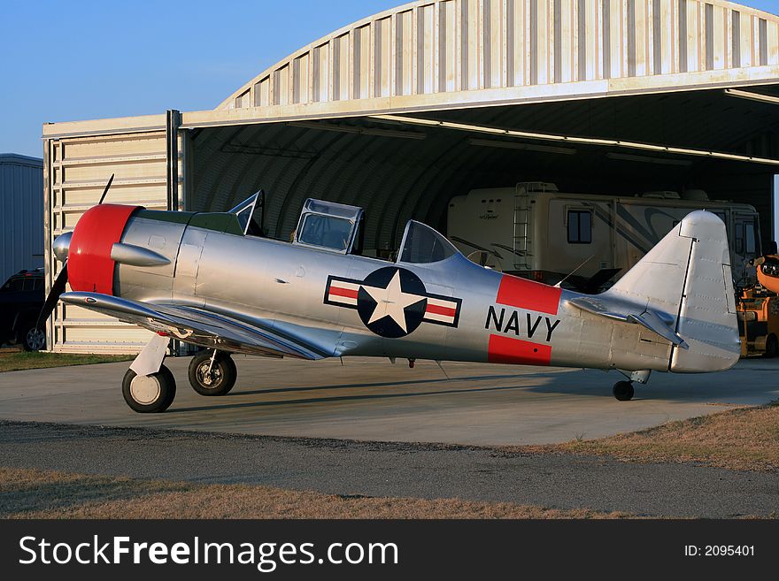 Old navy airplane in front of hanger. Old navy airplane in front of hanger