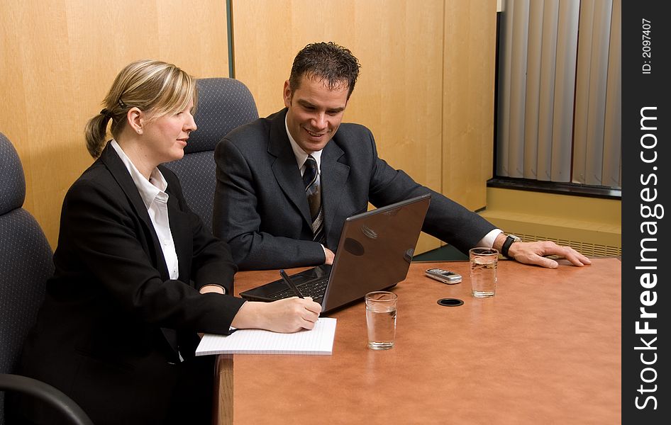 Business colleagues in a board room with a laptop. Business colleagues in a board room with a laptop