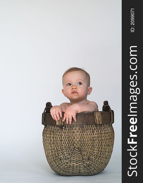 Image of cute baby sitting in a woven basket. Image of cute baby sitting in a woven basket