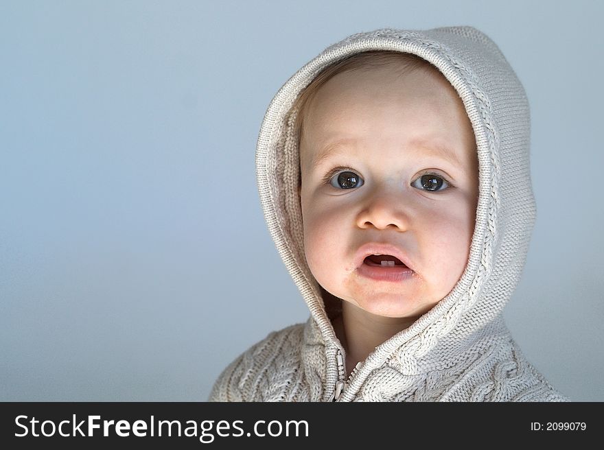 Image of cute baby wearing a hooded sweater, sitting in front of a white background. Image of cute baby wearing a hooded sweater, sitting in front of a white background