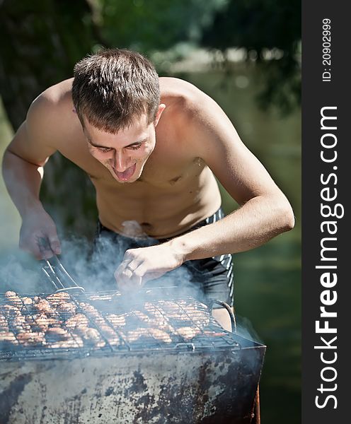 Young man preparing barbecue outdoors. Young man preparing barbecue outdoors