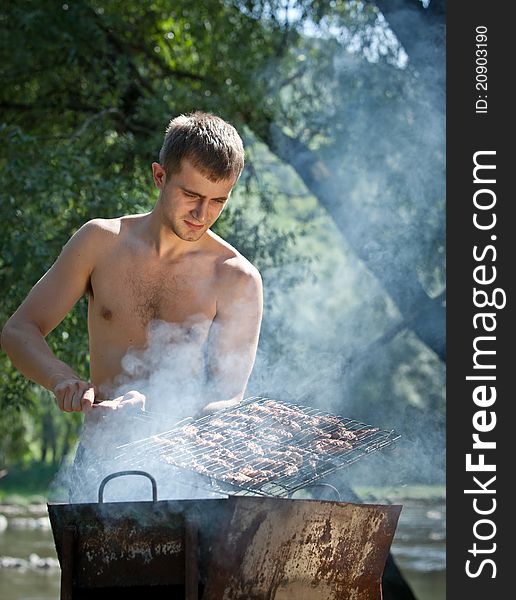 Young man preparing barbecue outdoors. Young man preparing barbecue outdoors