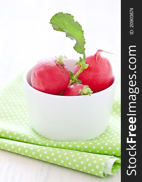 Fresh radish in bowl with green leaves