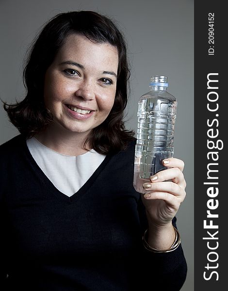 A young girl holding a water bottle with a big smile. A young girl holding a water bottle with a big smile.