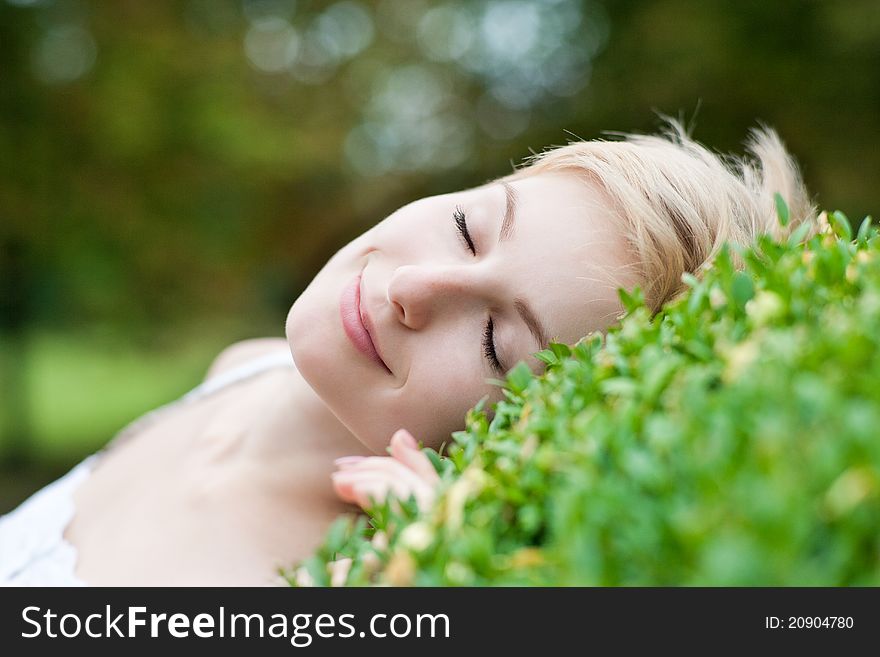 Outdoors portrait of cute young female lying on grass field at the park. Outdoors portrait of cute young female lying on grass field at the park